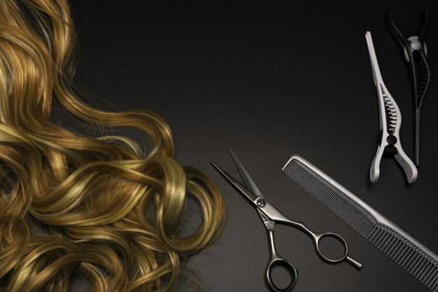Hairdressing set on a dark background, place for text. Blonde curl, scissors, hair clips and a comb.